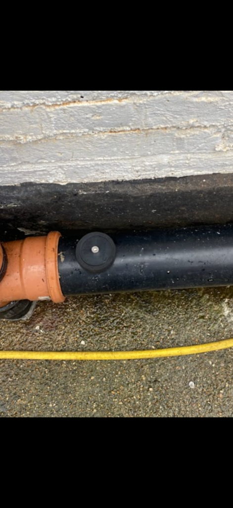 Capped access point on external black drain pipework in Bedford