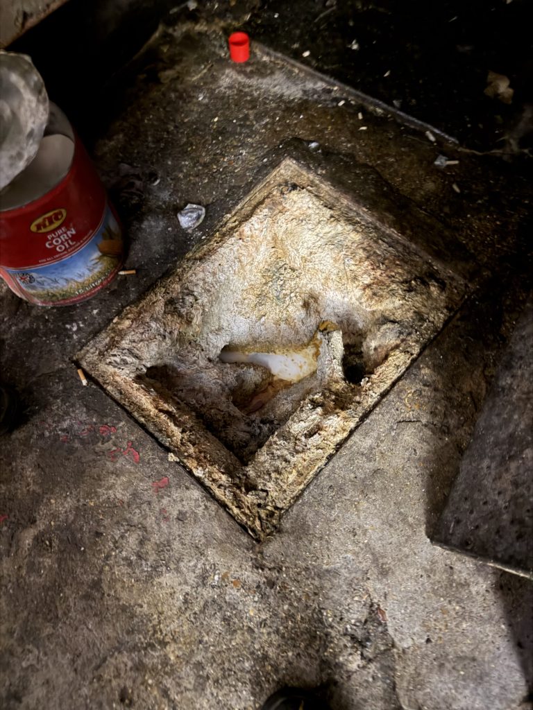Accumulated deposits visible inside a drainage access opening.
