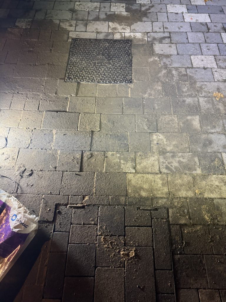 Block-paved surface with a drain inspection cover.