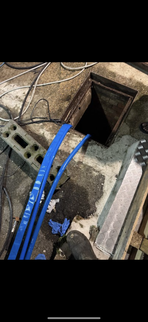 Blue drainage hoses entering an inspection chamber in Milton Keynes