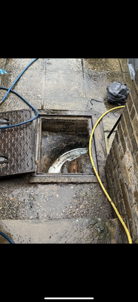 Open drainage chamber with hoses beside paving in Milton Keynes