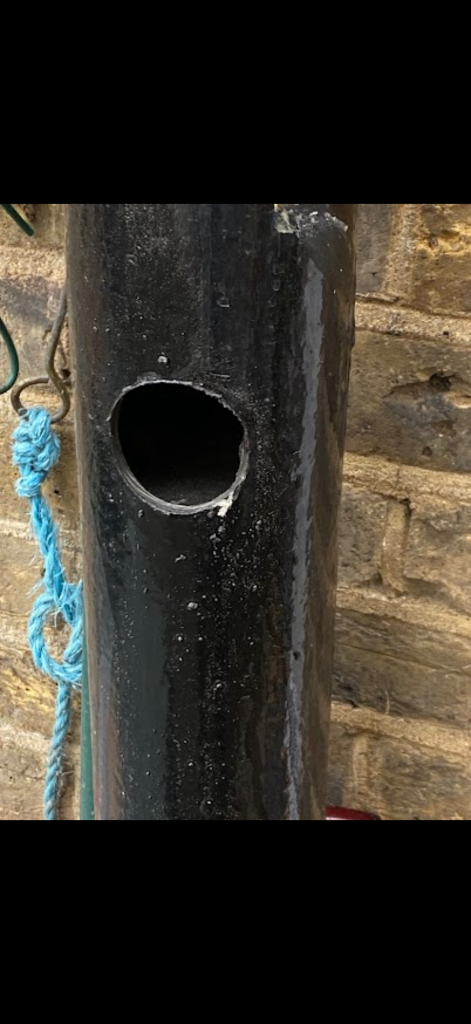 Circular opening in external black pipework beside a brick wall in Stevenage